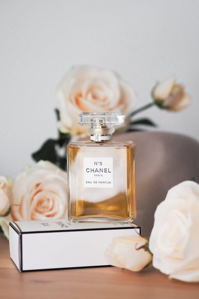 Chanel No. 5 perfume bottle surrounded by elegant roses on a wooden table.